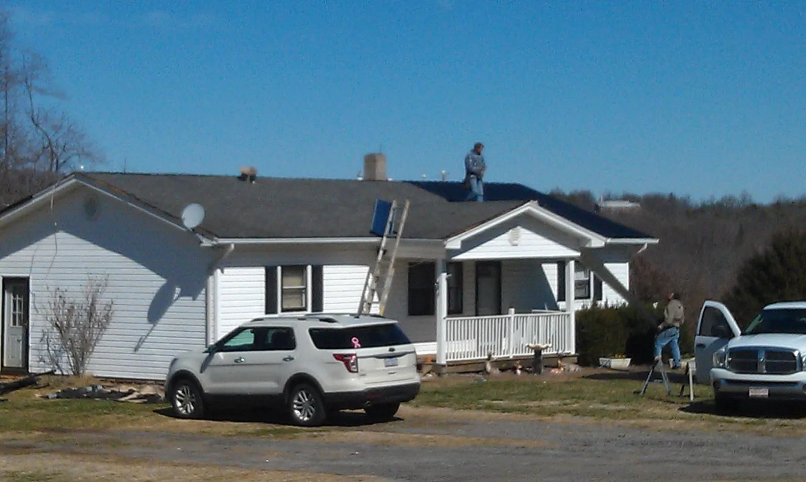 Roofers stripping shingles from a white ranch house roof in Wyoming